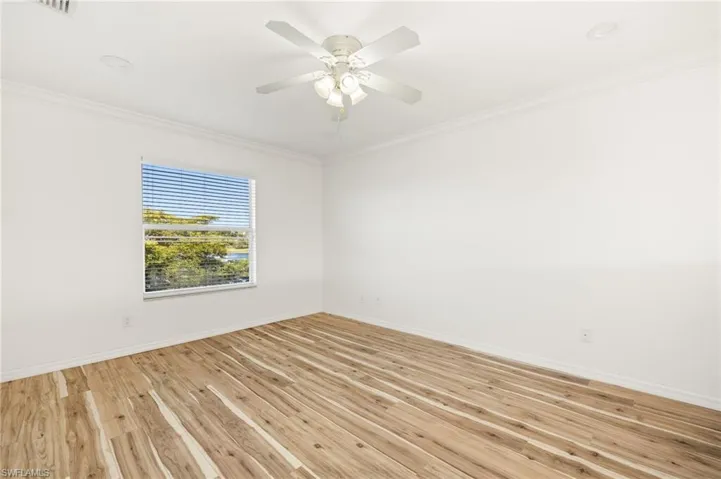 Unfurnished room featuring crown molding, light wood-style flooring, and a ceiling fan