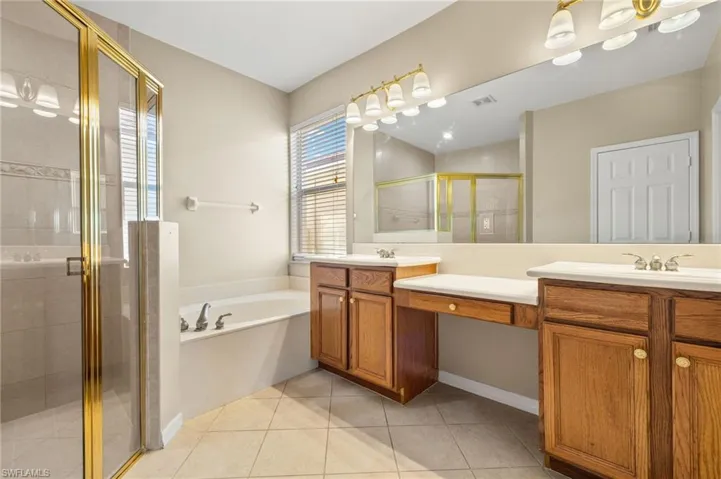 Bathroom featuring a shower stall, double vanity, a bath, and light tile patterned floors