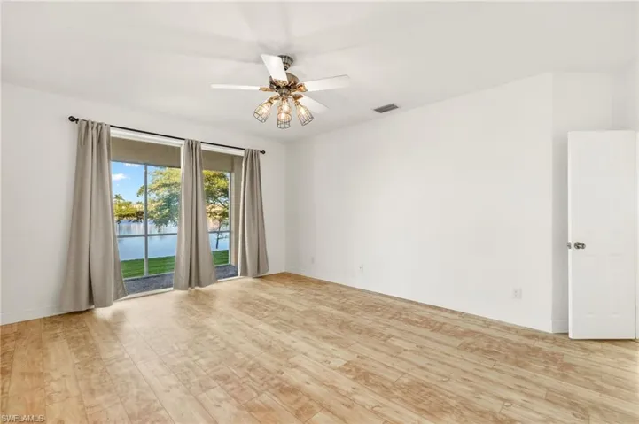 Spare room with ceiling fan, light wood-style floors, and a water view