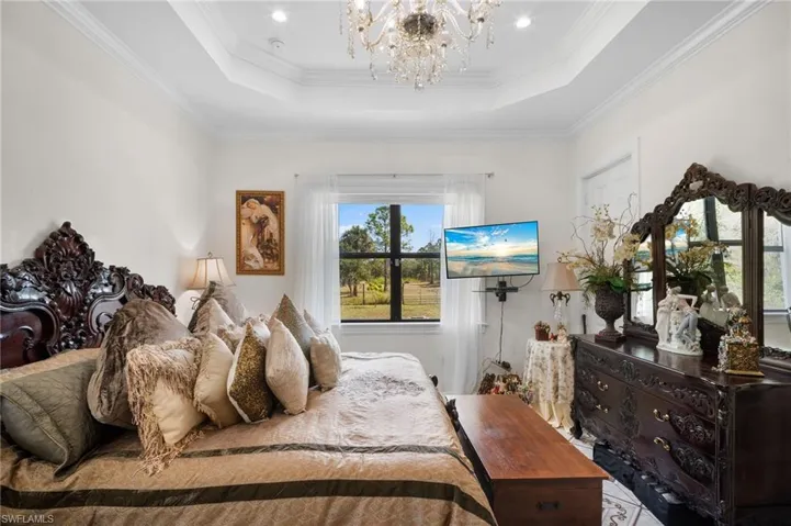Bedroom featuring crown molding, a tray ceiling, and a chandelier