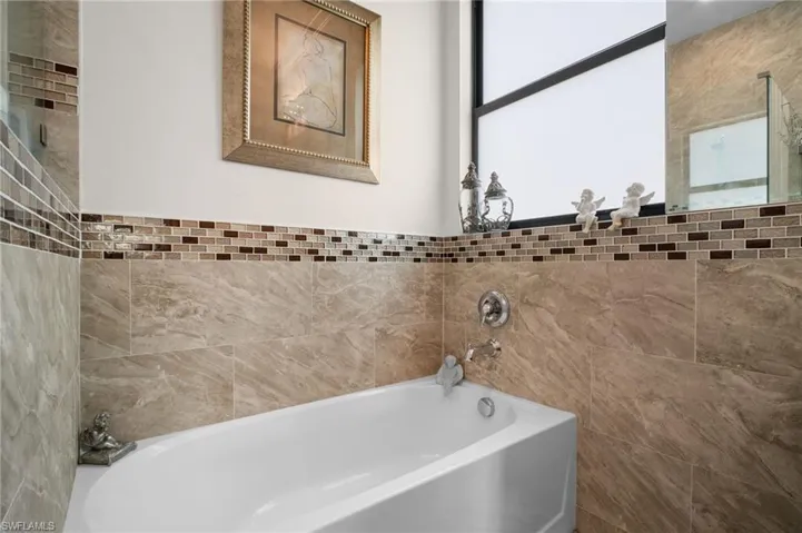 Bathroom with a garden tub and tile walls
