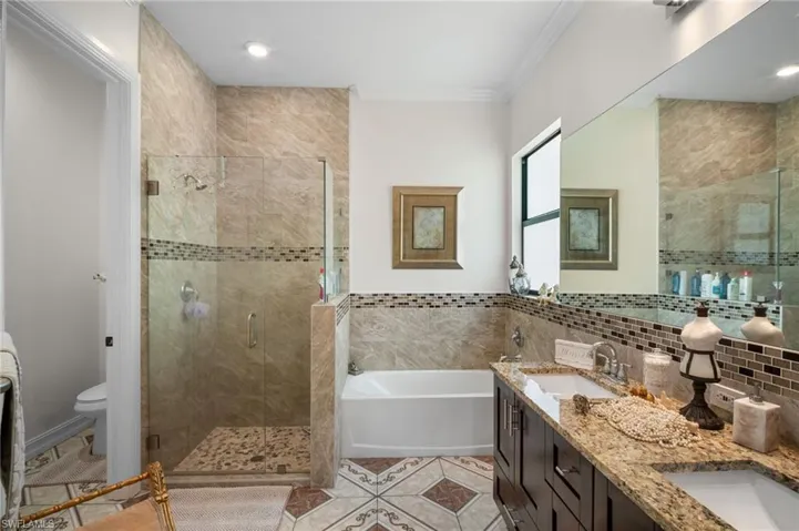 Bathroom featuring double vanity, a garden tub, a stall shower, light tile patterned floors, and crown molding