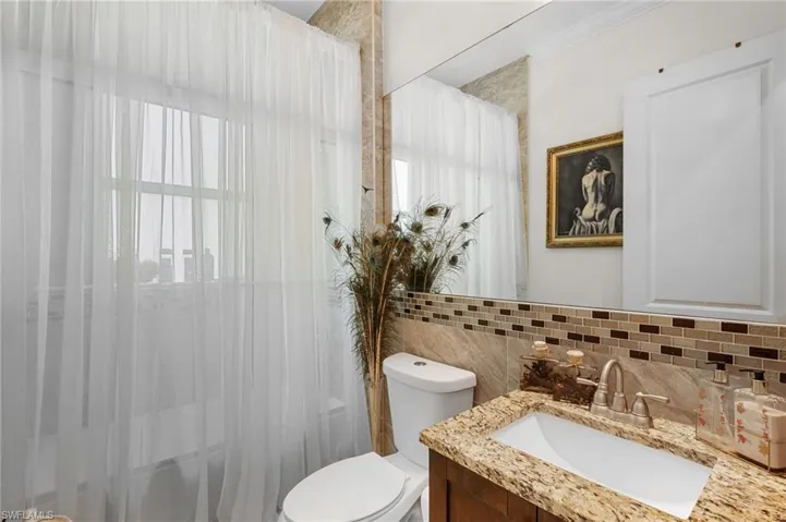 Full bath featuring vanity, tasteful backsplash, shower / tub combo with curtain, and ornamental molding