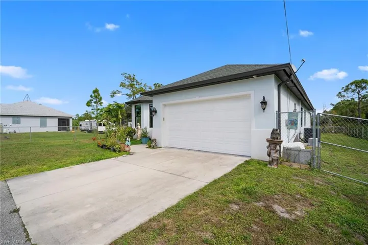 View of home's exterior featuring stucco siding, driveway, an attached garage, and a gate