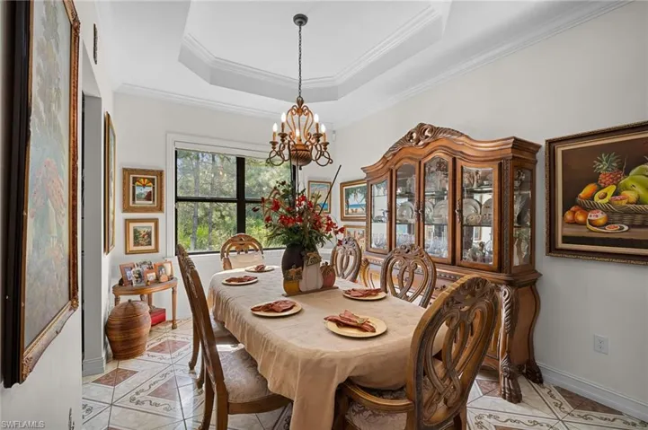 Dining area featuring ornamental molding, a chandelier, a raised ceiling, and light tile patterned floors