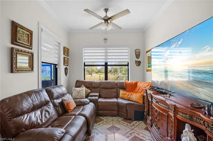 Living room with ornamental molding and a ceiling fan