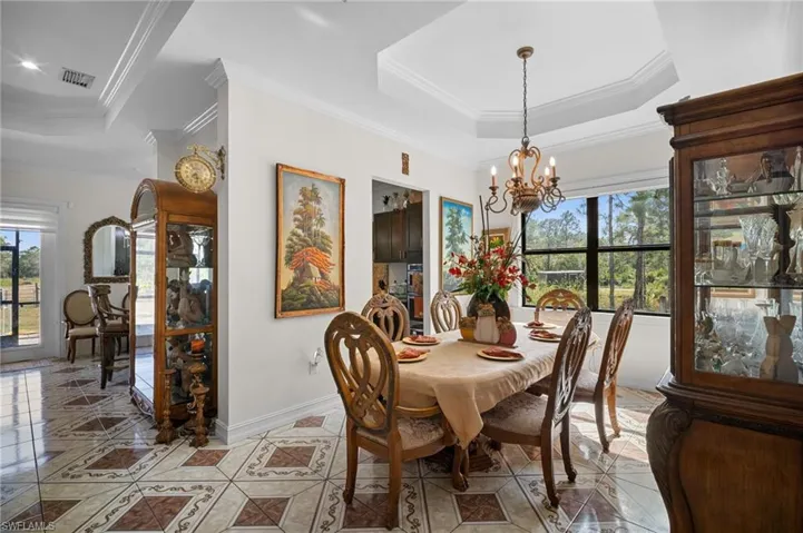 Dining room with ornamental molding, plenty of natural light, a tray ceiling, and a chandelier
