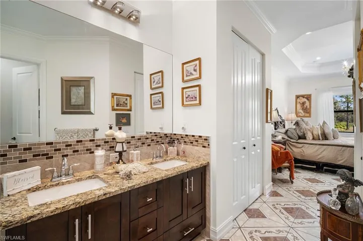 Full bathroom featuring ornamental molding, a raised ceiling, connected bathroom, double vanity, and backsplash