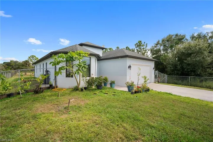 View of side of home with an attached garage, stucco siding, and driveway