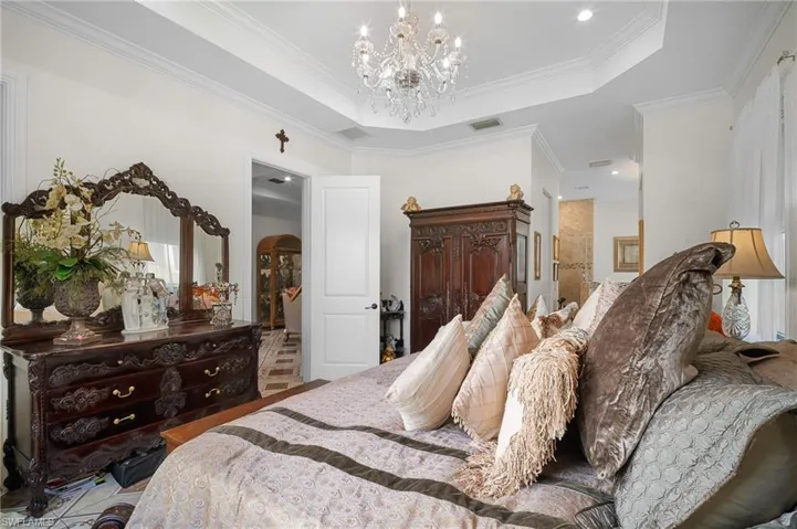 Bedroom with a tray ceiling, crown molding, a chandelier, and recessed lighting