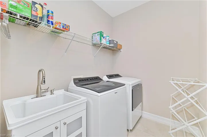 Laundry area featuring independent washer and dryer and light tile patterned flooring