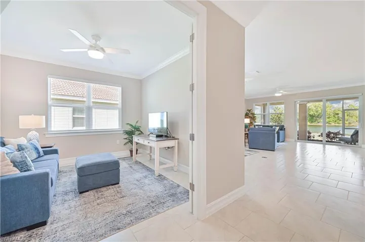 Living room with a ceiling fan, crown molding, and light tile patterned flooring