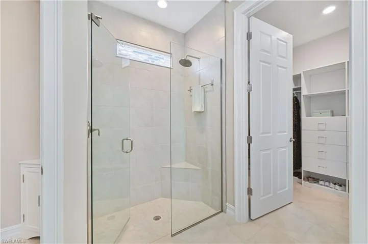 Full bathroom with a spacious closet, a shower stall, and recessed lighting