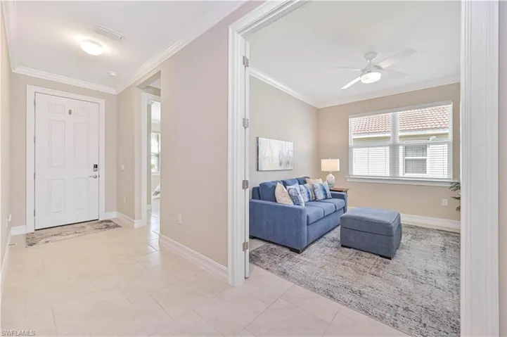 Foyer with ornamental molding, a ceiling fan, and light tile patterned flooring
