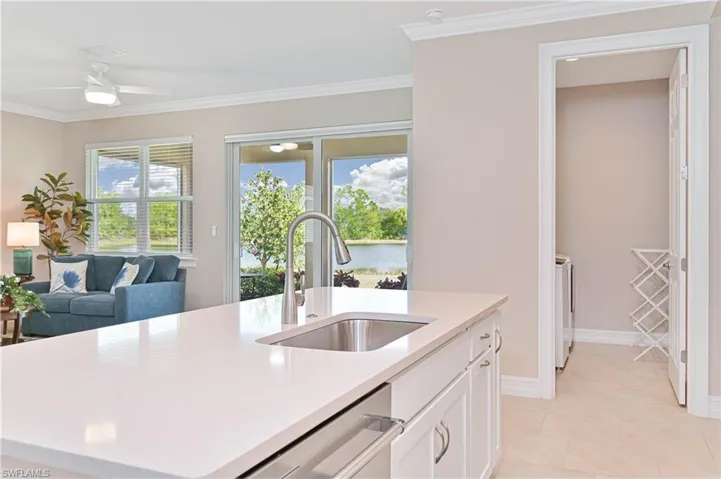 Kitchen featuring white cabinets, ornamental molding, a center island with sink, dishwasher, and separate washer and dryer