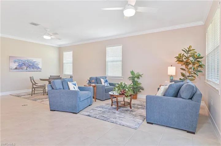 Living room with a ceiling fan, crown molding, and light tile patterned floors