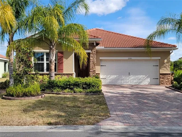 View of front facade featuring stone siding, stucco siding, decorative driveway, and a garage