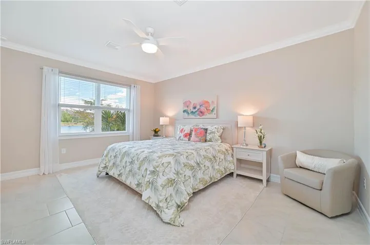Bedroom with ornamental molding, light tile patterned floors, and ceiling fan