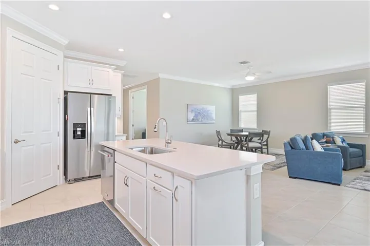 Kitchen with white cabinets, stainless steel appliances, open floor plan, ornamental molding, and recessed lighting