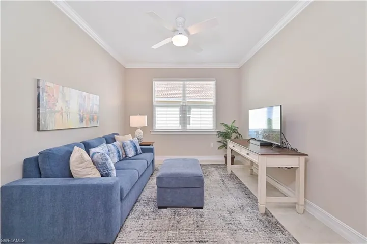 Living area with ceiling fan, ornamental molding, and tile patterned floors