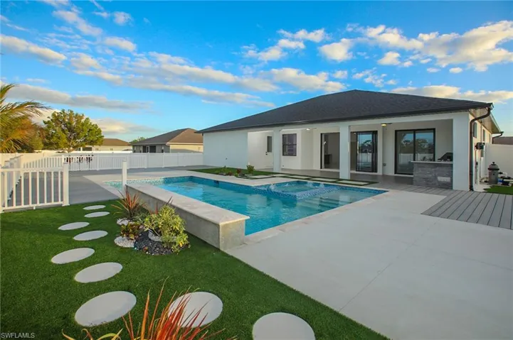 View of pool featuring an in ground hot tub, ceiling fan, exterior kitchen, a patio area, and a lawn