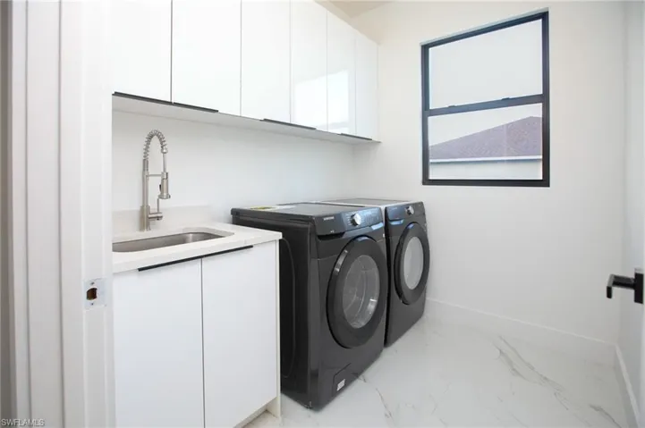 Washroom featuring cabinets, independent washer and dryer, and sink