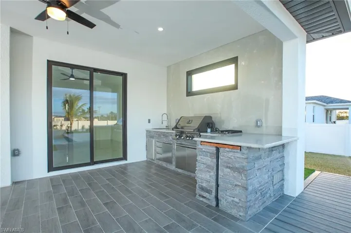 View of patio / terrace featuring an outdoor kitchen, ceiling fan, a grill, and a wet bar
