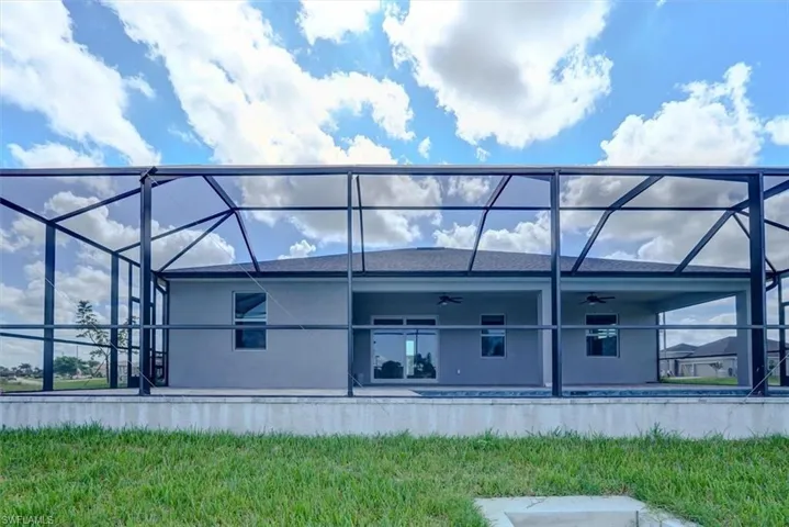 Back of property with ceiling fan, a lanai, and a patio area