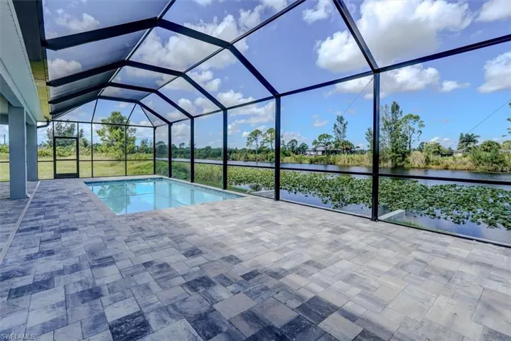 View of swimming pool featuring a water view, a lanai, and a patio area