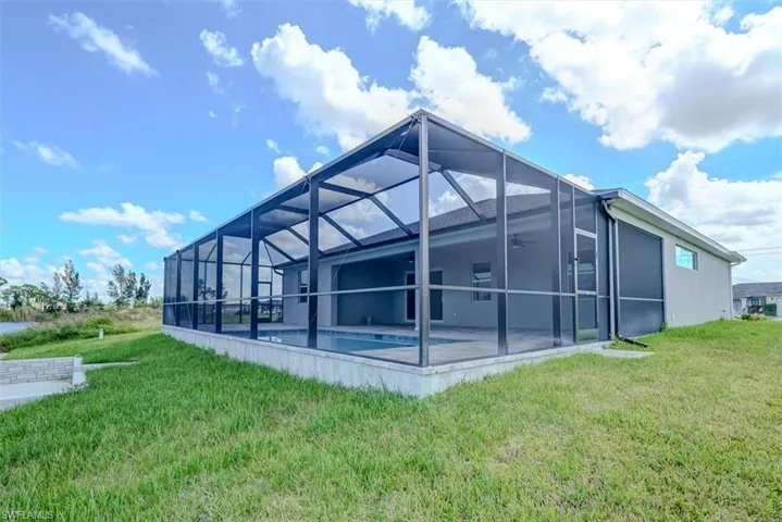 Rear view of property featuring a yard, glass enclosure, and a patio area