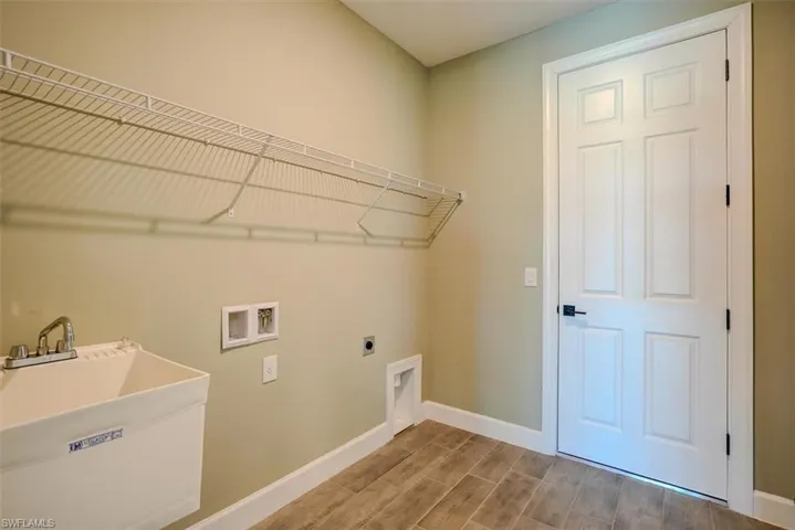 Laundry room featuring hookup for an electric dryer, sink, hardwood / wood-style flooring, and hookup for a washing machine