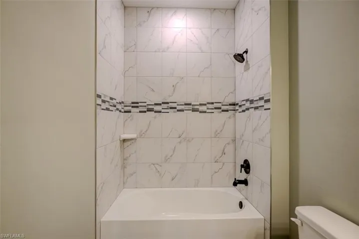 Bathroom featuring tiled shower / bath combo and toilet