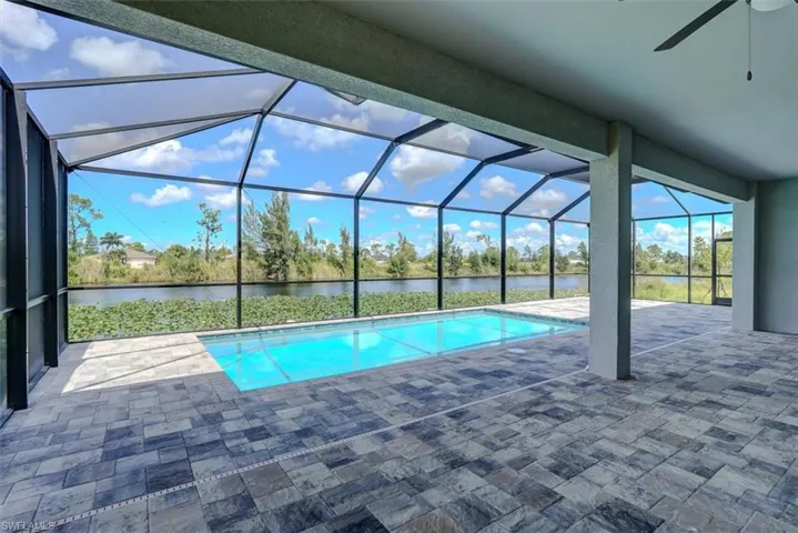 View of swimming pool featuring a lanai, a patio, a water view, and ceiling fan