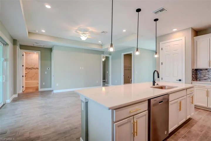 Kitchen with a center island with sink, stainless steel dishwasher, sink, and ceiling fan