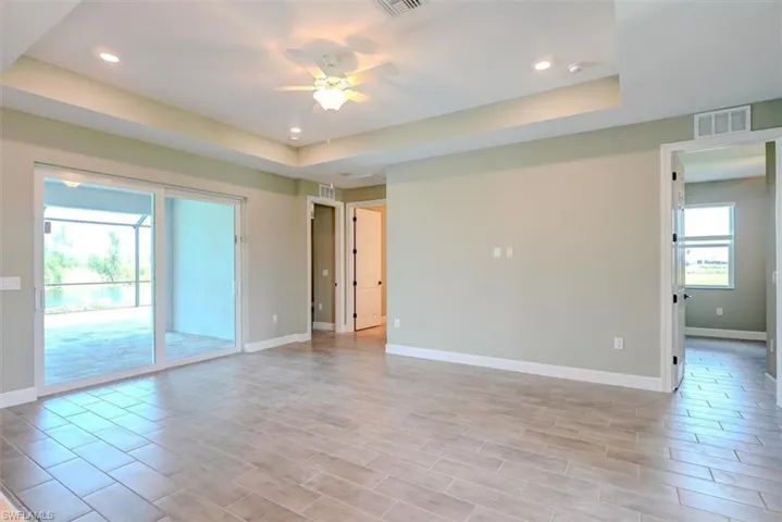 Spare room with light wood-type flooring, a tray ceiling, and ceiling fan