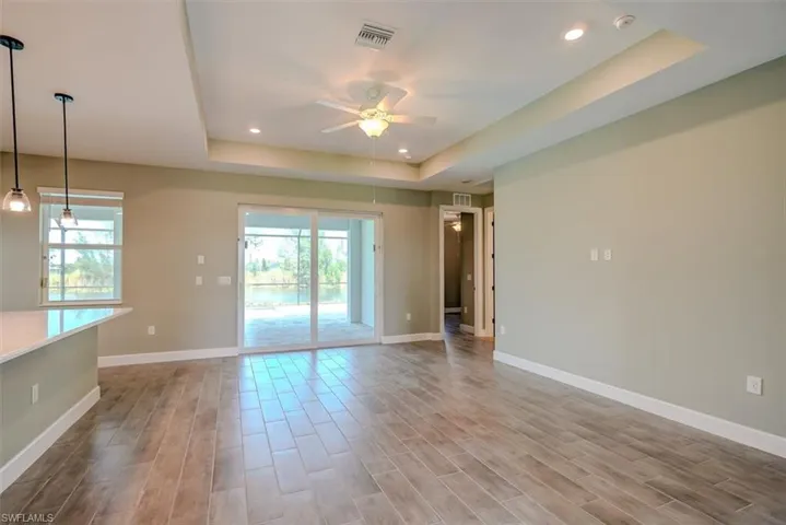 Spare room featuring a raised ceiling, ceiling fan, and light hardwood / wood-style flooring
