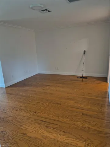 Spare room with dark wood-type flooring and ornamental molding