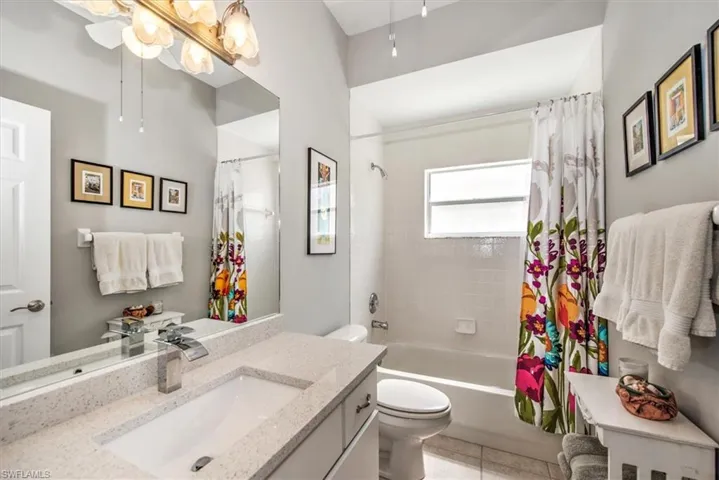 Full guest bathroom featuring vanity, shower / bath combo with shower curtain, toilet, and tile floors