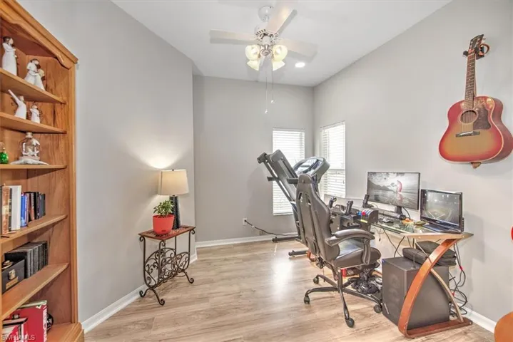 Office/Den space featuring light wood-type flooring, ceiling fan, pocketing doors