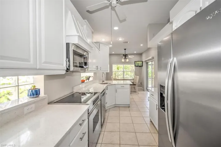 Kitchen with breakfast bar, sink, white cabinetry, light tile floors and appliances with stainless steel finishes, slide in range NEW refrigerator,