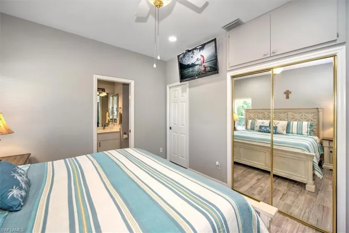 Main Bedroom featuring 2 closets (1 is walk-in), light wood-style flooring, ensuite bath, 2 sinks, and ceiling fan
