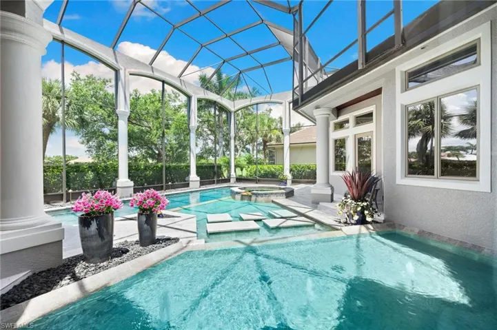 View of swimming pool with glass enclosure, a patio, and a pool with connected hot tub