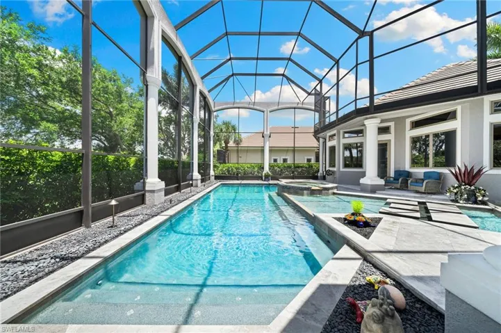 View of swimming pool with a patio area, a pool with connected hot tub, and glass enclosure