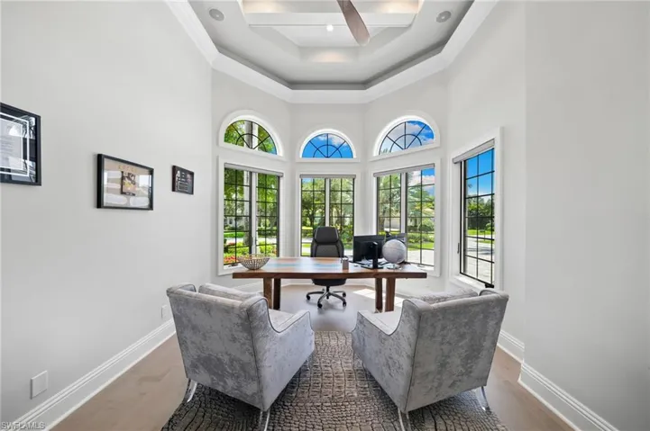 Home office featuring wood finished floors, coffered ceiling, a ceiling fan, ornamental molding, and beamed ceiling