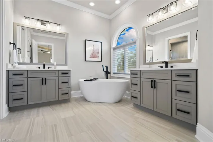 Full bath with two vanities, ornamental molding, a soaking tub, ceiling fan, and recessed lighting