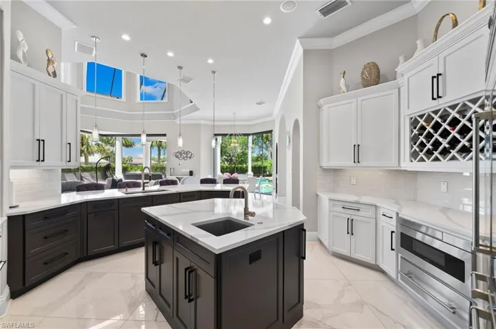Kitchen with light marble finish floors, a peninsula, crown molding, white cabinets, and recessed lighting