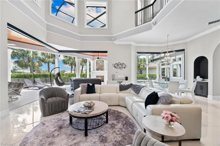 Living area with a high ceiling, healthy amount of natural light, arched walkways, a chandelier, and marble finish flooring
