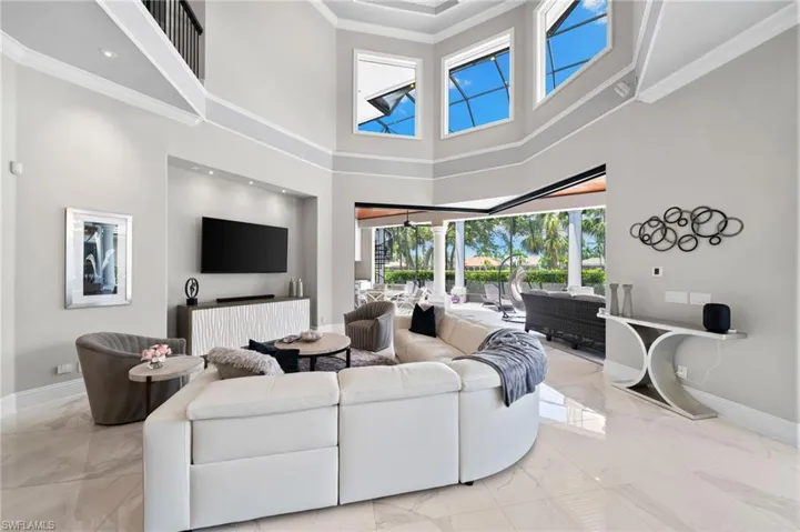Living room featuring marble tiled flooring, a towering ceiling, and ornamental molding