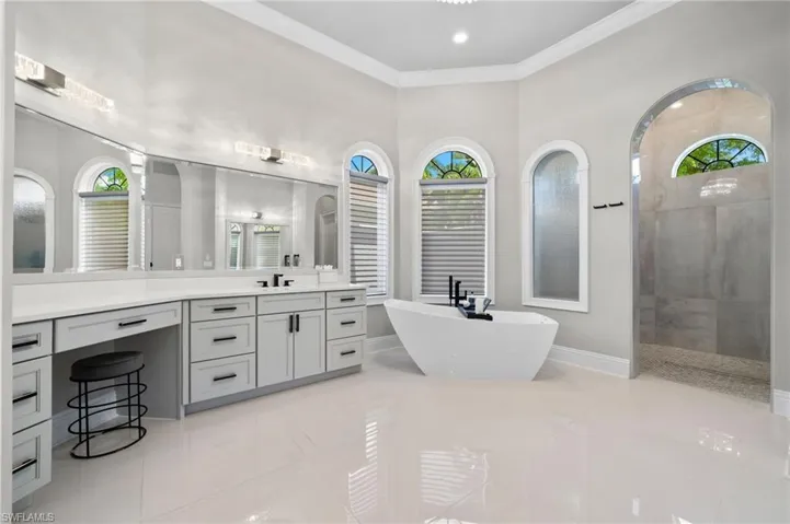Full bath with a freestanding tub, ornamental molding, vanity, walk in shower, and tile patterned flooring
