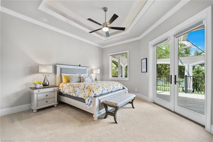 Bedroom with a raised ceiling, light carpet, access to exterior, crown molding, and french doors